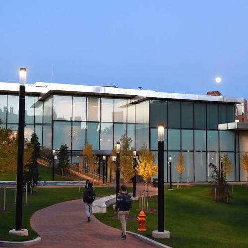 Moon rises over campus building at dusk